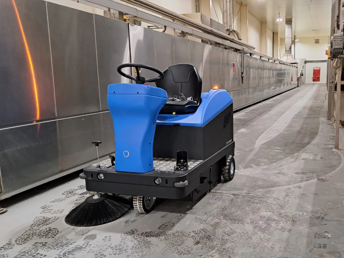 Conquest HD90 ride-on sweeper operating in an industrial facility, delivering efficient dust and debris collection on hard floors
