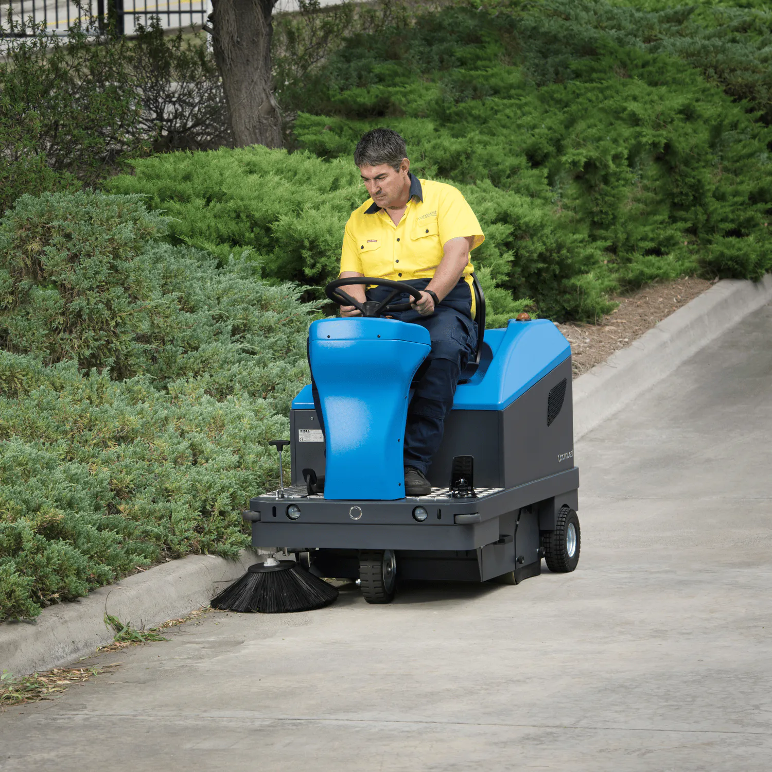 Conquest HD90 ride-on sweeper operated outdoors, sweeping paved commercial areas with reliable dust control and productivity