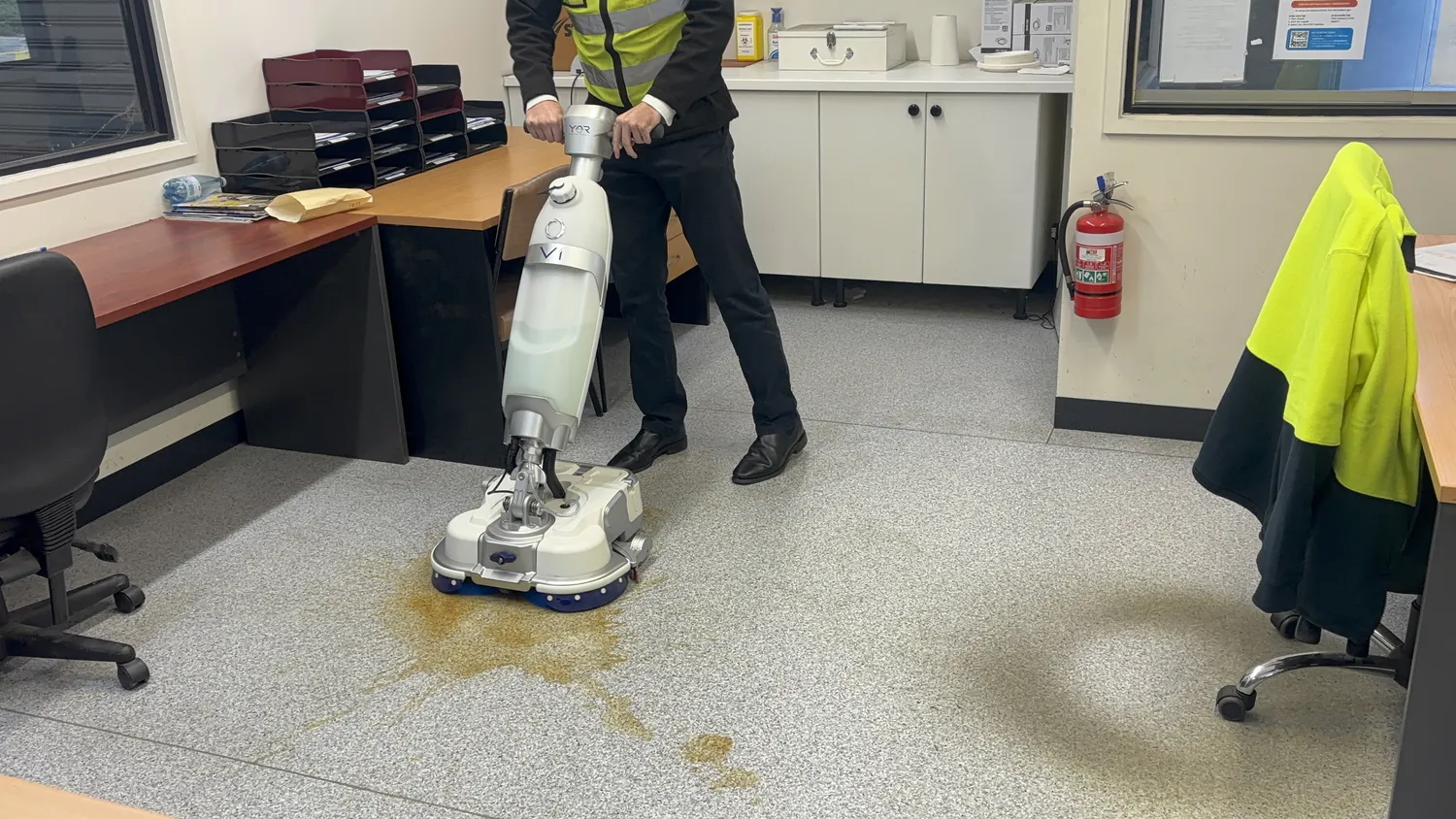 Conquest HDS46 walk-behind floor scrubber removing spills from office flooring with compact and manoeuvrable cleaning performance
