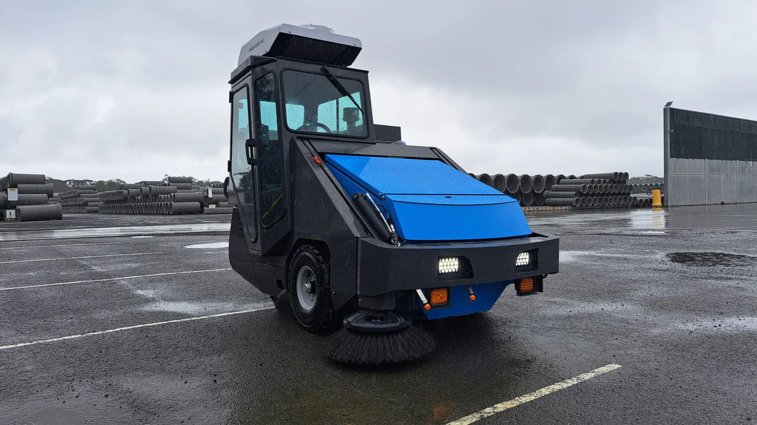 Conquest SD180-HEPA ride-on sweeper operating in an industrial yard with advanced HEPA dust control technology