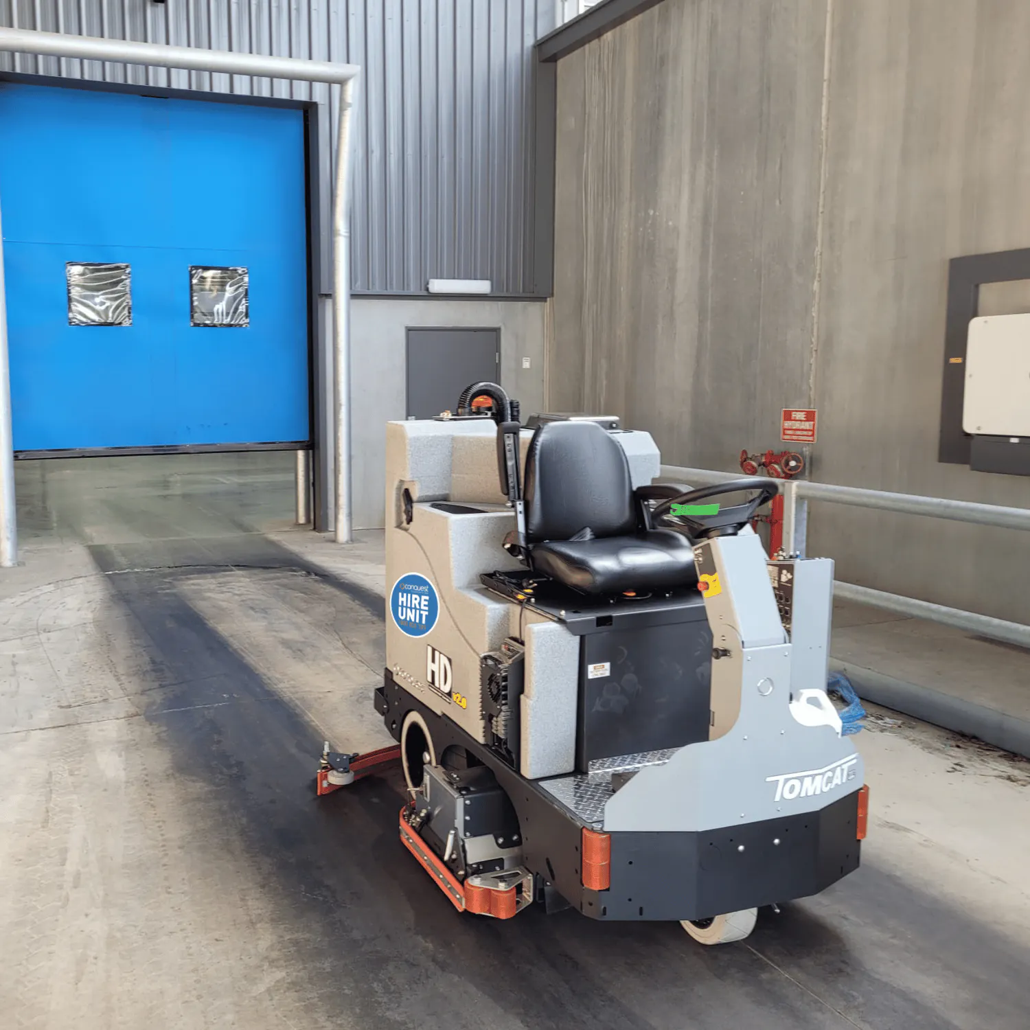 Conquest SDS115 ride-on scrubber cleaning a commercial loading dock and warehouse entrance